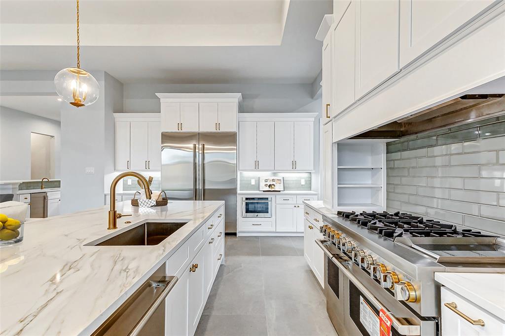 Bright Maribelle kitchen with a stone island, white cabinetry, and brass fixtures